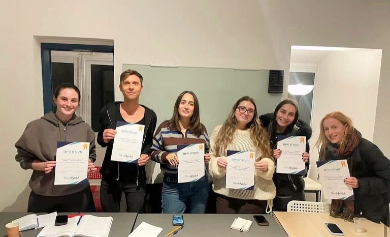 Six smiling students holding their Hebrew course completion certificates