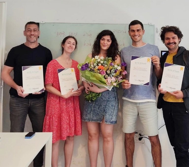 Graduates with certificates and a bouquet of flowers at the Integraliah classroom